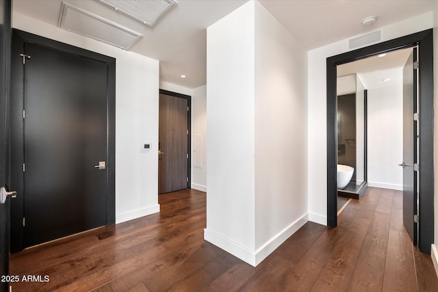 hallway with dark wood-style floors, baseboards, and visible vents