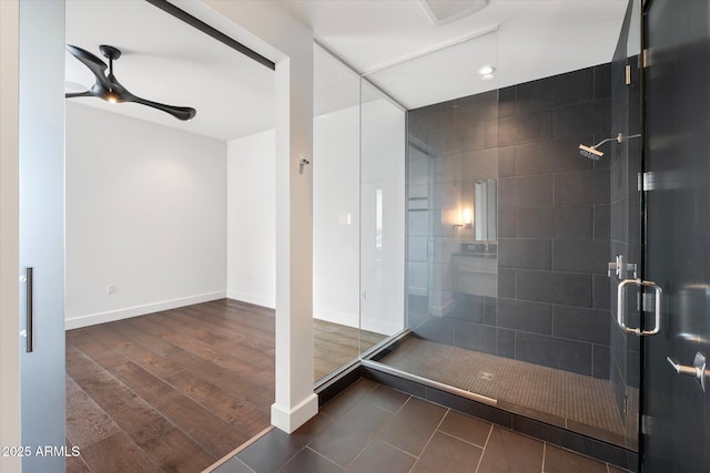 full bathroom featuring a stall shower, baseboards, a ceiling fan, and wood finished floors