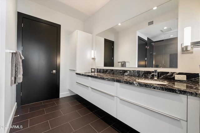 full bathroom featuring visible vents, a sink, a shower stall, and double vanity