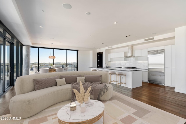 living area featuring floor to ceiling windows, wood finished floors, visible vents, and recessed lighting