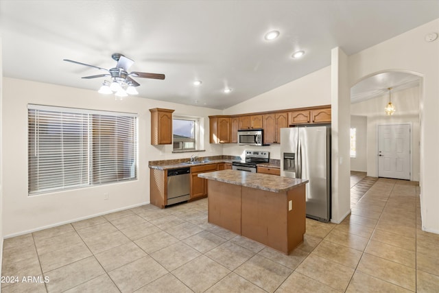 kitchen with lofted ceiling, ceiling fan, light tile patterned floors, a kitchen island, and stainless steel appliances