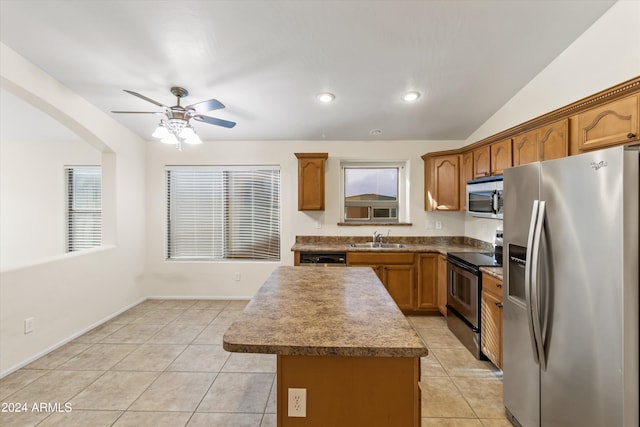 kitchen with appliances with stainless steel finishes, sink, light tile patterned floors, a center island, and lofted ceiling