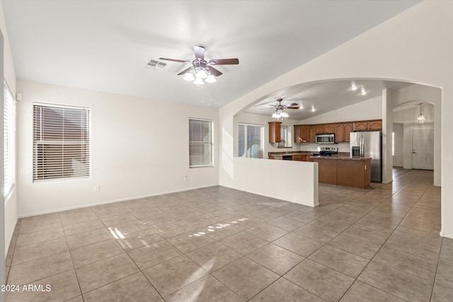 unfurnished living room featuring ceiling fan, light tile patterned floors, and vaulted ceiling