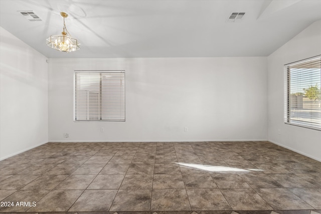 tiled empty room with a notable chandelier and vaulted ceiling