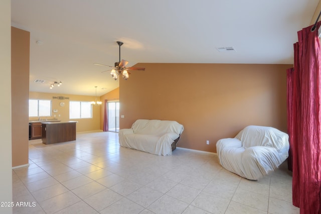 sitting room featuring lofted ceiling, light tile patterned flooring, and ceiling fan with notable chandelier