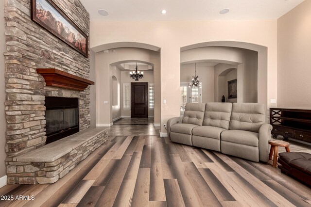 5226 S Fairchild Ln, Chandler, AZ 85249 - living area with arched walkways, wood finished floors, a fireplace, a chandelier, and baseboards