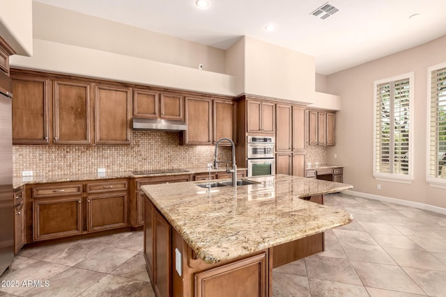 5226 S Fairchild Ln, Chandler, AZ 85249 - kitchen with a sink, black electric cooktop, brown cabinets, under cabinet range hood, and backsplash