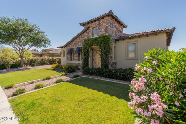 5226 S Fairchild Ln, Chandler, AZ 85249 - mediterranean / spanish house featuring stone siding, a front yard, stucco siding, and a tiled roof