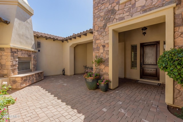 5226 S Fairchild Ln, Chandler, AZ 85249 - entrance to property featuring an outdoor stone fireplace, stone siding, a patio area, and stucco siding