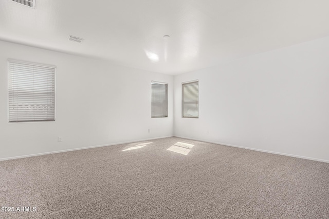 empty room featuring carpet flooring, visible vents, and baseboards