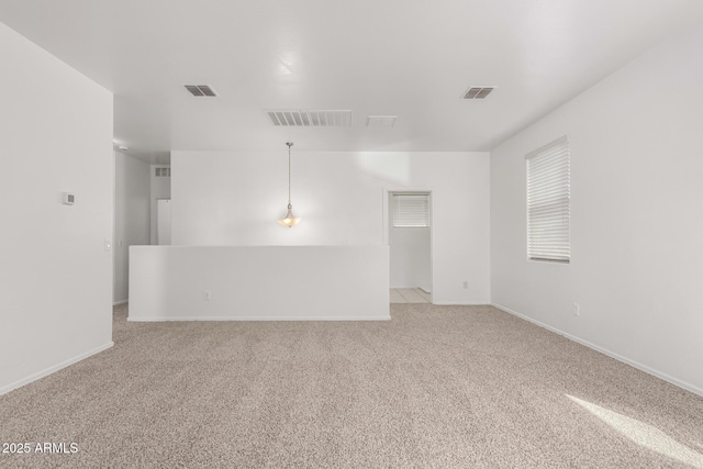 spare room featuring light carpet, baseboards, and visible vents