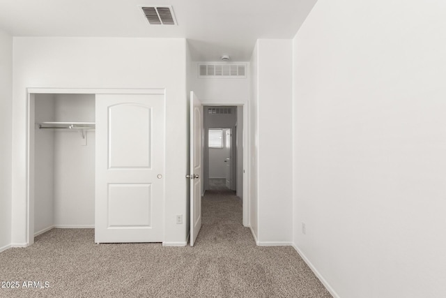 unfurnished bedroom featuring baseboards, a closet, visible vents, and light colored carpet