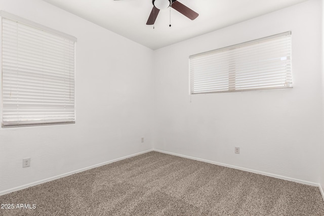 carpeted spare room with ceiling fan and baseboards