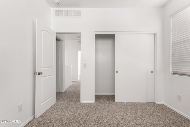 unfurnished bedroom with a closet, carpet flooring, visible vents, and baseboards