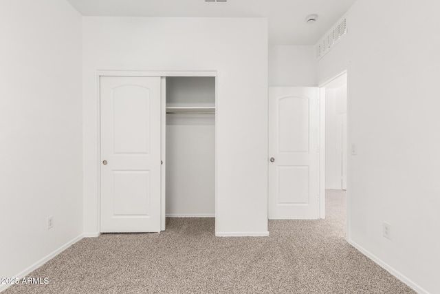 unfurnished bedroom featuring a closet, carpet flooring, visible vents, and baseboards