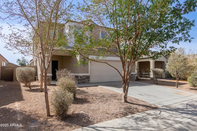 view of front of house featuring a garage, stone siding, concrete driveway, and stucco siding