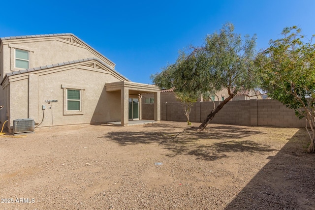 rear view of property with central AC, a fenced backyard, and stucco siding