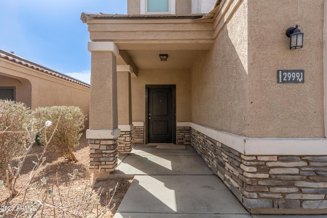 doorway to property featuring stone siding and stucco siding