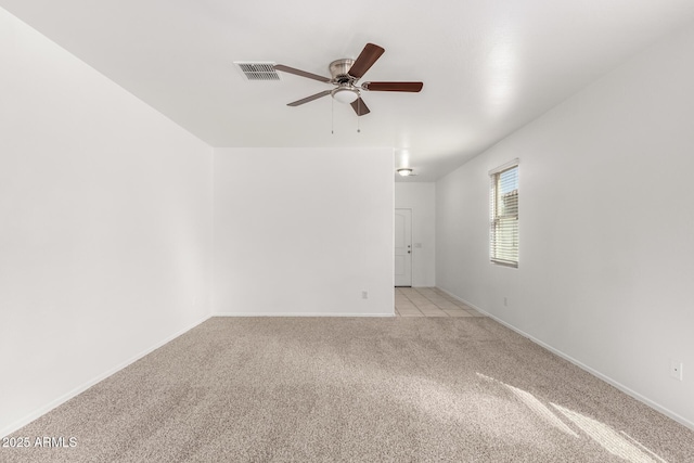 spare room with light carpet, baseboards, visible vents, and a ceiling fan