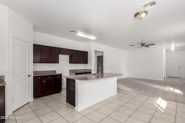 kitchen featuring ceiling fan, stone counters, light colored carpet, a sink, and visible vents