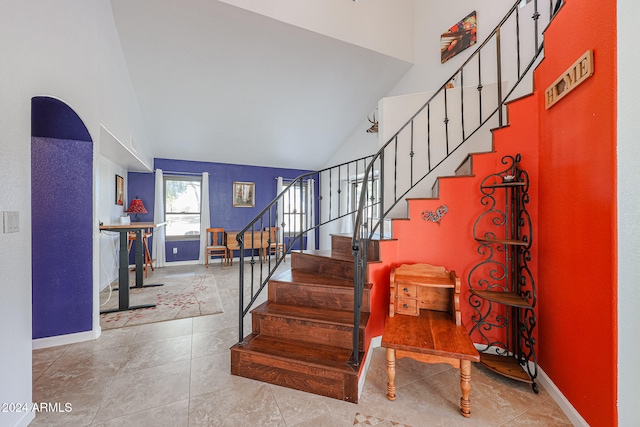 stairway with tile patterned floors and high vaulted ceiling