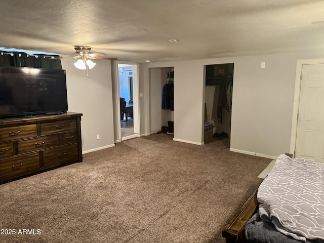 bedroom featuring a ceiling fan, ensuite bathroom, a textured ceiling, dark carpet, and baseboards