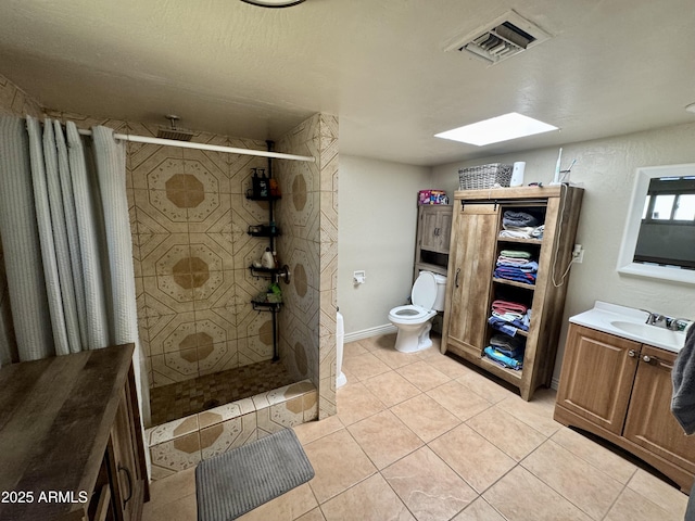 bathroom with tile patterned flooring, visible vents, a skylight, tiled shower, and vanity