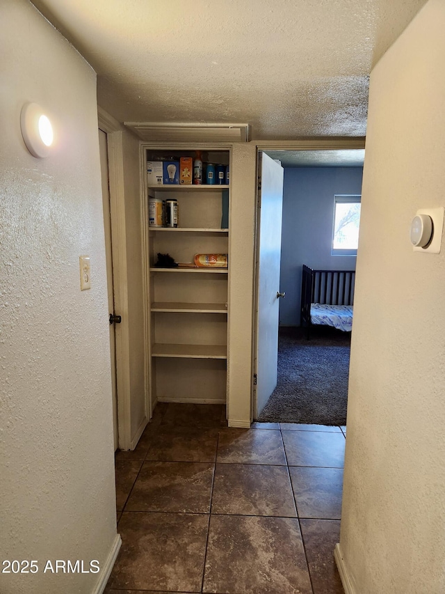 hallway with a textured ceiling and a textured wall