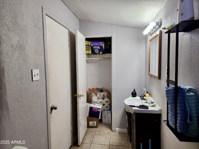 bathroom with a textured wall, vanity, and tile patterned flooring