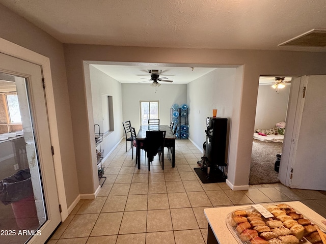 dining space featuring visible vents, a textured ceiling, light tile patterned floors, baseboards, and ceiling fan