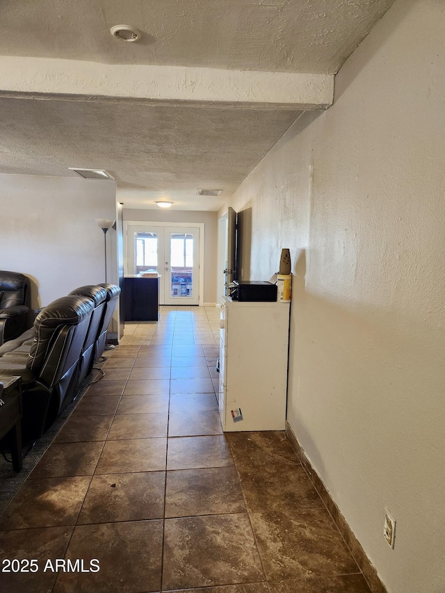 hallway with beamed ceiling, visible vents, a textured ceiling, french doors, and baseboards