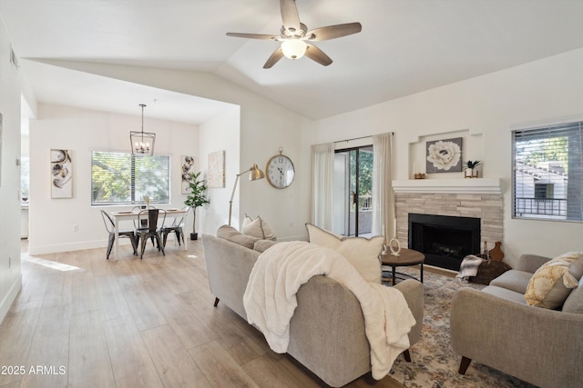 living room featuring ceiling fan with notable chandelier, a healthy amount of sunlight, wood-type flooring, and vaulted ceiling