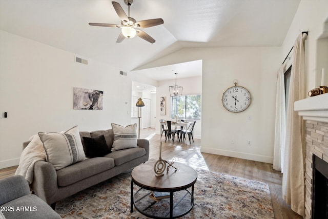 living room with a stone fireplace, hardwood / wood-style floors, lofted ceiling, and ceiling fan