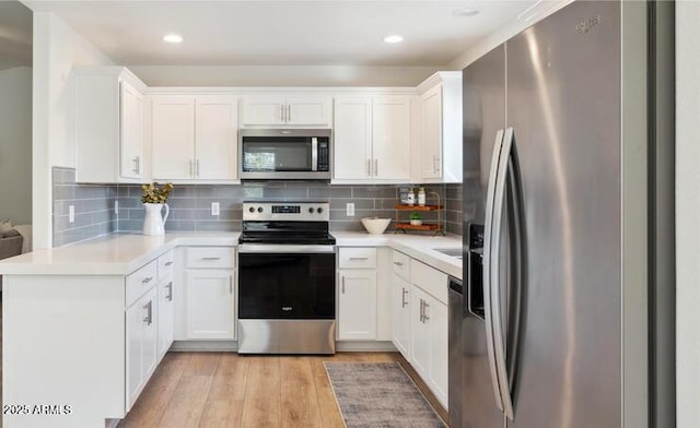 kitchen featuring backsplash, stainless steel appliances, light wood-type flooring, and white cabinets