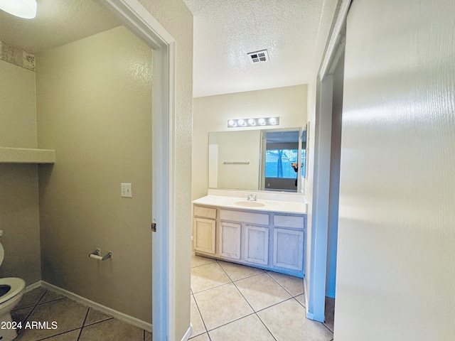 bathroom featuring vanity, tile patterned floors, a textured ceiling, and toilet