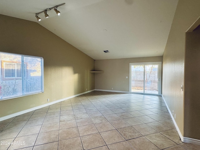 tiled spare room with track lighting and vaulted ceiling