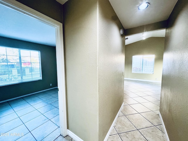 corridor with lofted ceiling and light tile patterned floors