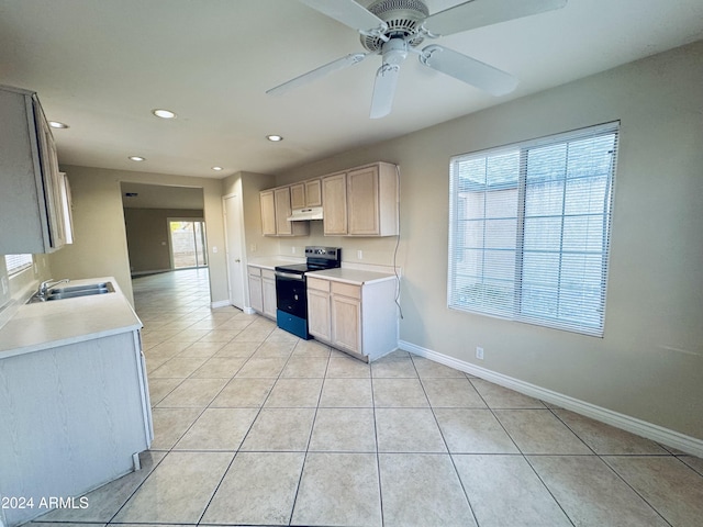 kitchen with electric range, light tile patterned floors, sink, and light brown cabinetry