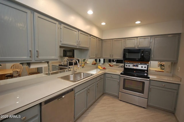kitchen featuring a sink, stainless steel appliances, light wood finished floors, light countertops, and gray cabinetry