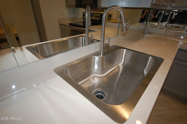room details with stainless steel range with electric cooktop, a sink, and light countertops