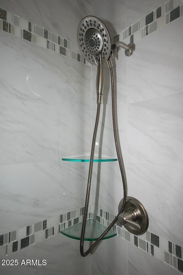 interior details with a tile shower and a sink