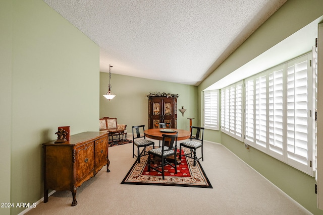 dining room featuring lofted ceiling, carpet, and a textured ceiling