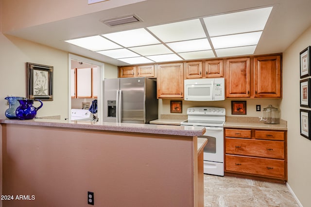 kitchen with kitchen peninsula, independent washer and dryer, and white appliances