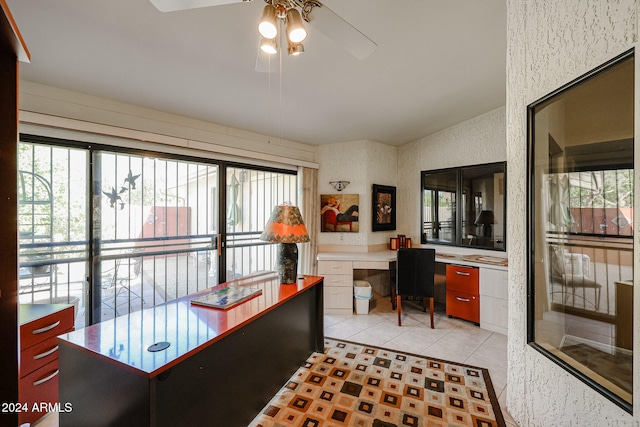 tiled office with ceiling fan, lofted ceiling, and built in desk