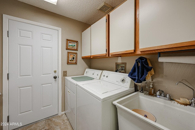 washroom with washing machine and dryer, cabinets, sink, and a textured ceiling