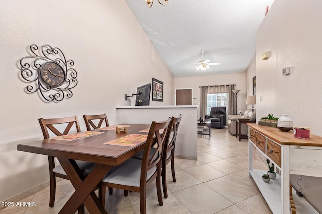 dining space with a textured ceiling, ceiling fan, light tile patterned floors, baseboards, and vaulted ceiling