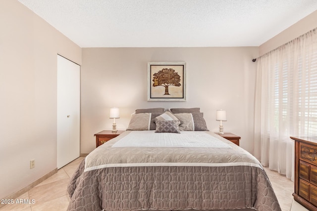 bedroom with a textured ceiling, a closet, and light tile patterned flooring