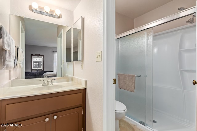 ensuite bathroom featuring vanity, a stall shower, connected bathroom, and toilet