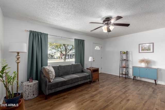 living room with ceiling fan, dark wood-type flooring, and a textured ceiling