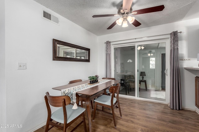 dining space with ceiling fan, dark wood-type flooring, and a textured ceiling